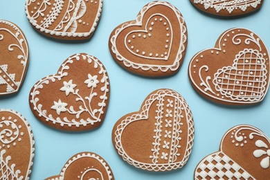 Photo of Tasty heart shaped gingerbread cookies on light blue background, flat lay