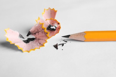 Photo of One sharp graphite pencil and shavings on white background, closeup