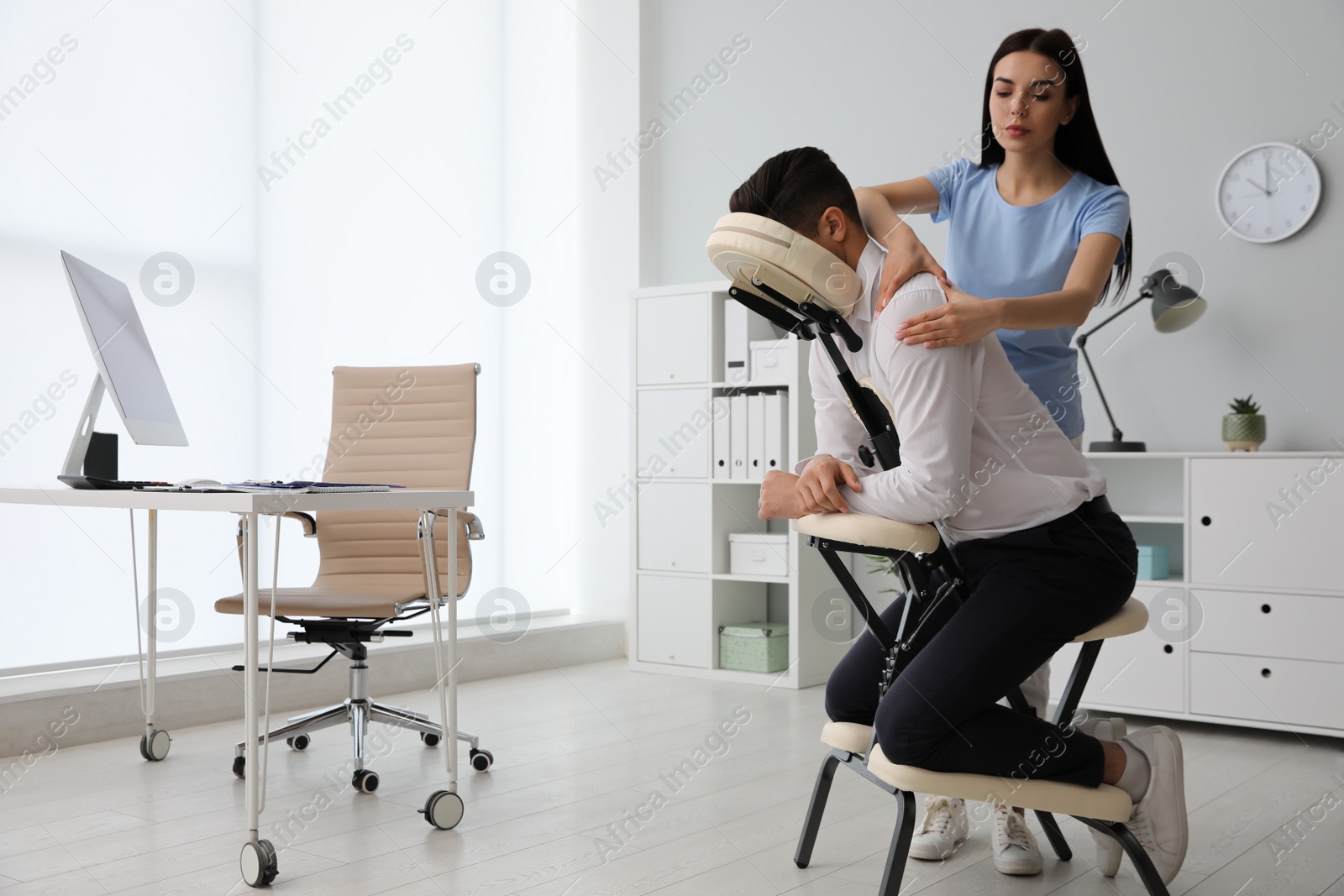 Photo of Man receiving massage in modern chair indoors