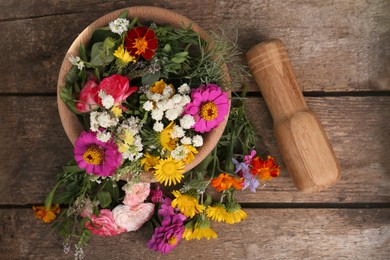 Photo of Mortar, pestle and different flowers on wooden table, top view
