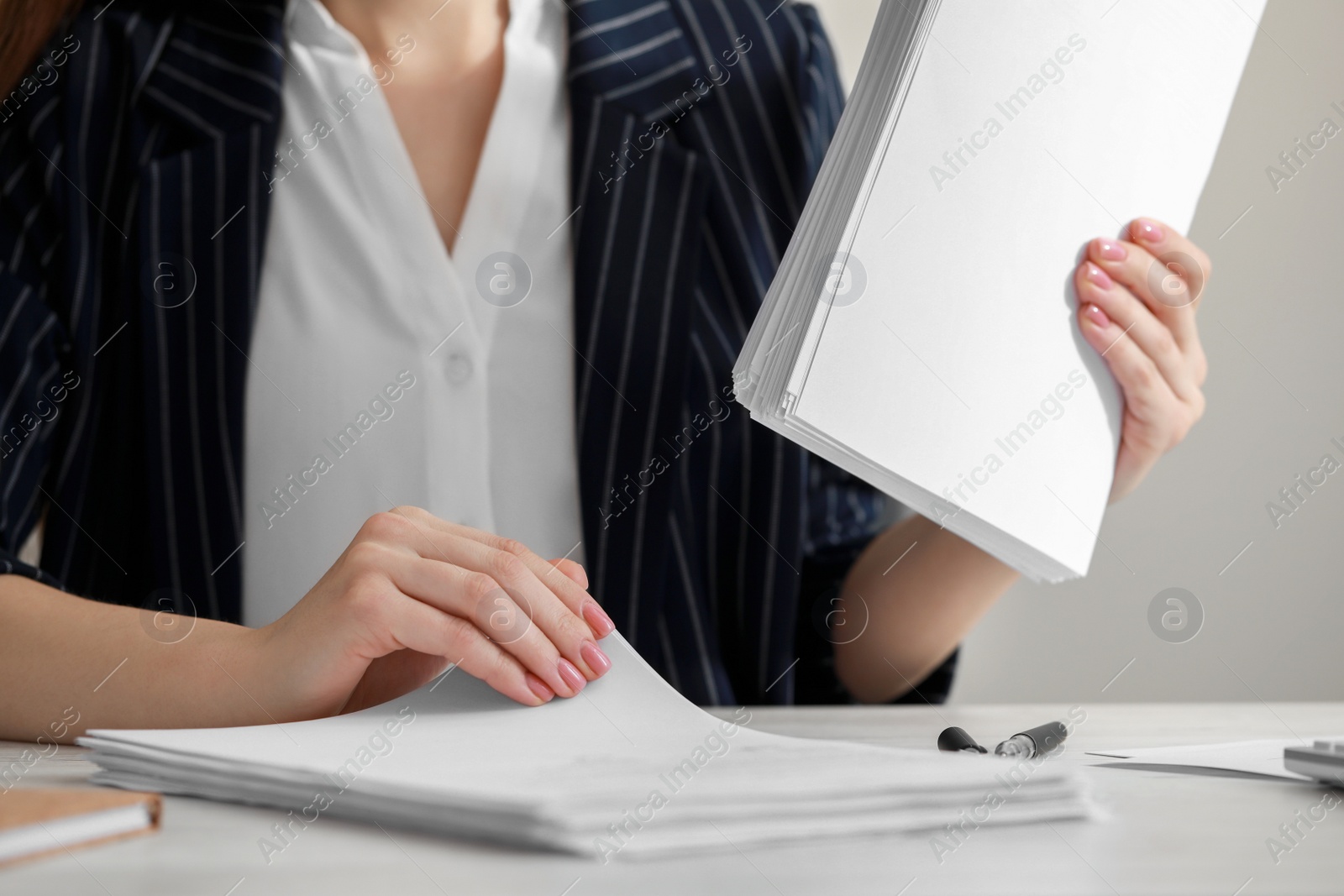 Photo of Woman reading documents at white table in office, closeup