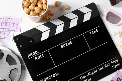 Photo of Flat lay composition with clapperboard and popcorn on white wooden table