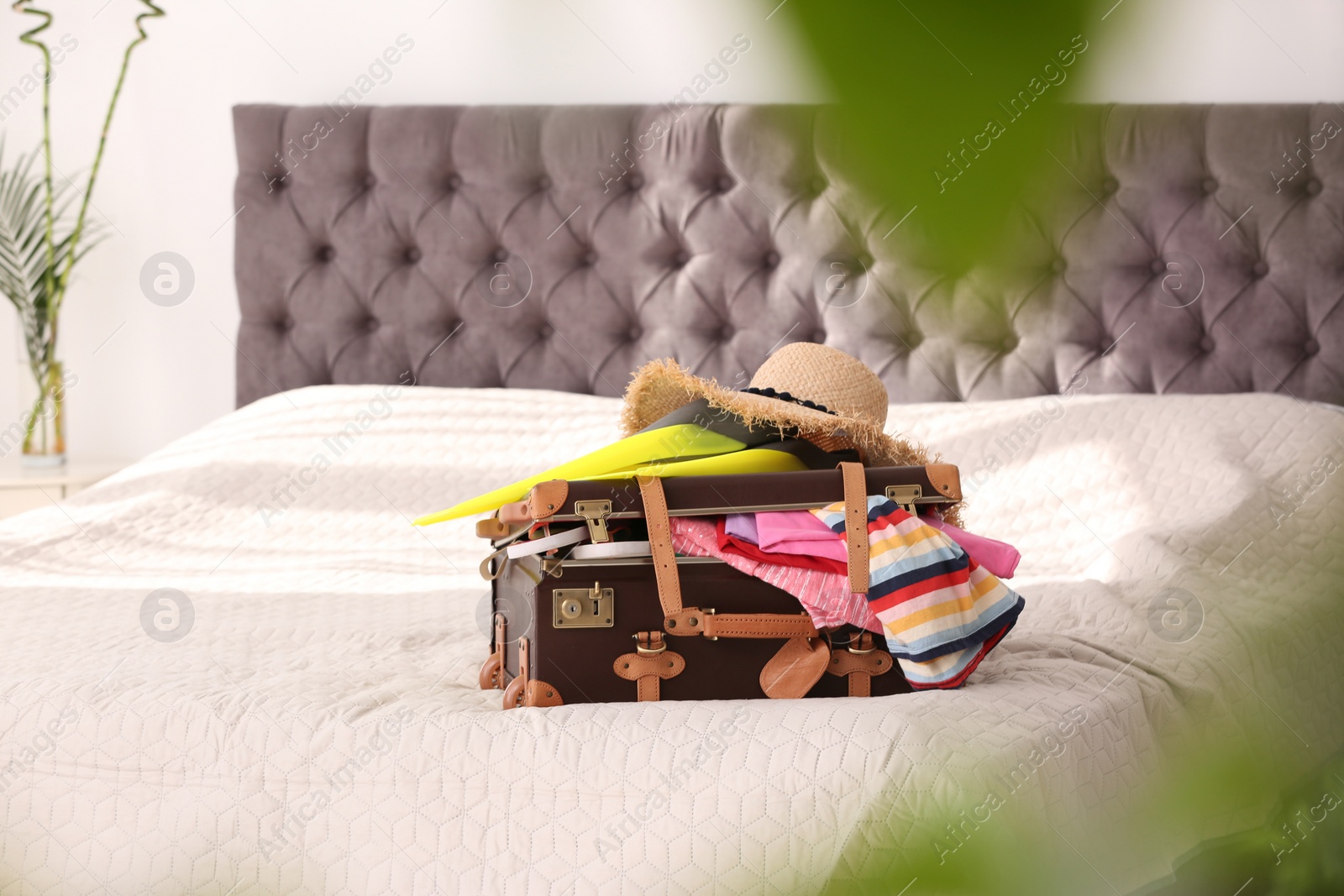 Photo of Vintage suitcase full of clothes on bed indoors