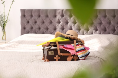 Photo of Vintage suitcase full of clothes on bed indoors