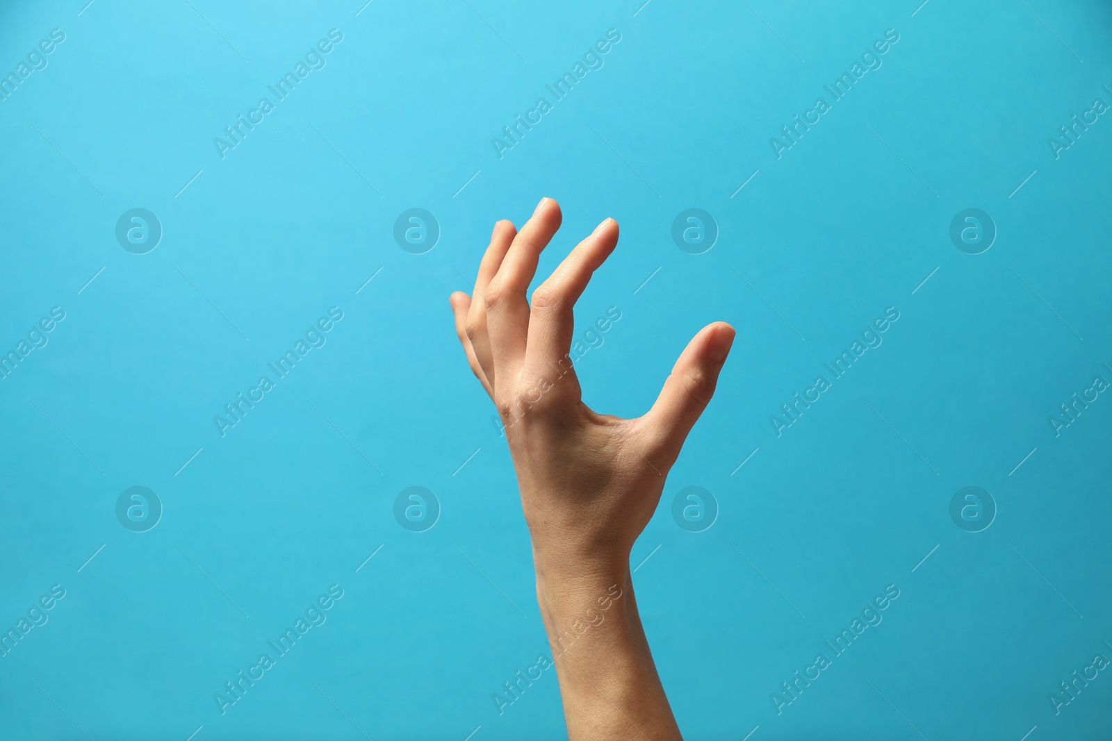 Photo of Woman holding something in hand on light blue background, closeup