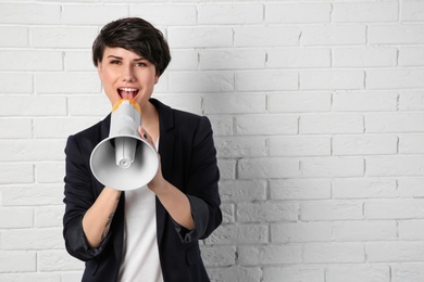 Photo of Young woman with megaphone on brick wall background