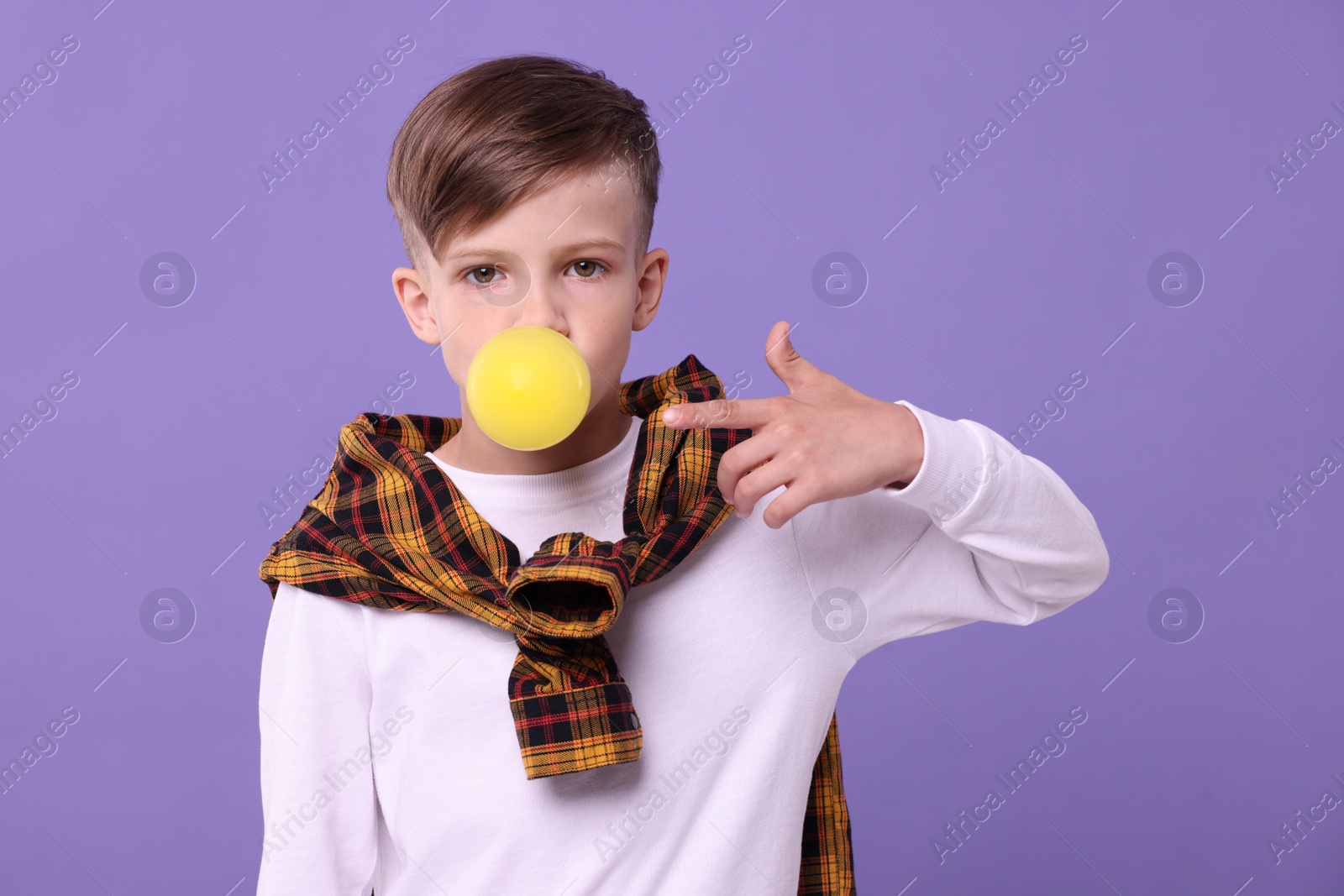 Photo of Boy blowing bubble gum on purple background
