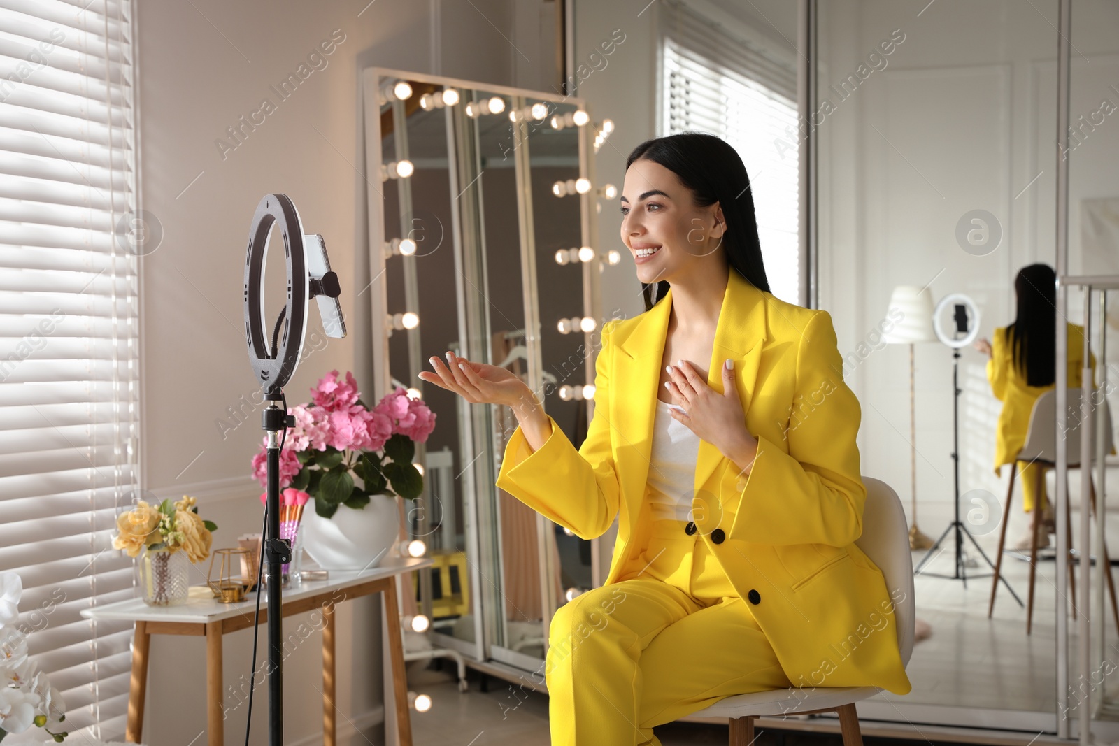 Photo of Blogger recording video in dressing room at home. Using ring lamp and smartphone