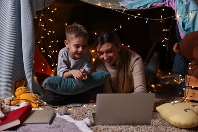 Mother and her son with laptop in play tent at home