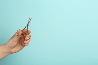 Photo of Woman holding sewing scissors on light blue background, closeup. Space for text