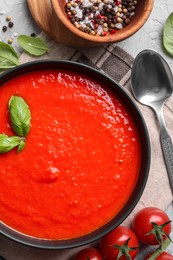 Delicious tomato cream soup served on grey textured table, flat lay