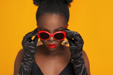 Photo of Fashionable portrait of beautiful woman with stylish sunglasses on yellow background