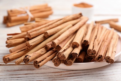 Photo of Aromatic cinnamon sticks on white wooden table, closeup