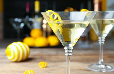 Glass of Lemon Drop Martini cocktail with zest on table against blurred background, closeup. Space for text