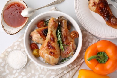 Photo of Marinade, roasted chicken drumsticks and other products on white table, flat lay