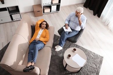 Photo of Professional psychotherapist working with patient in office, above view