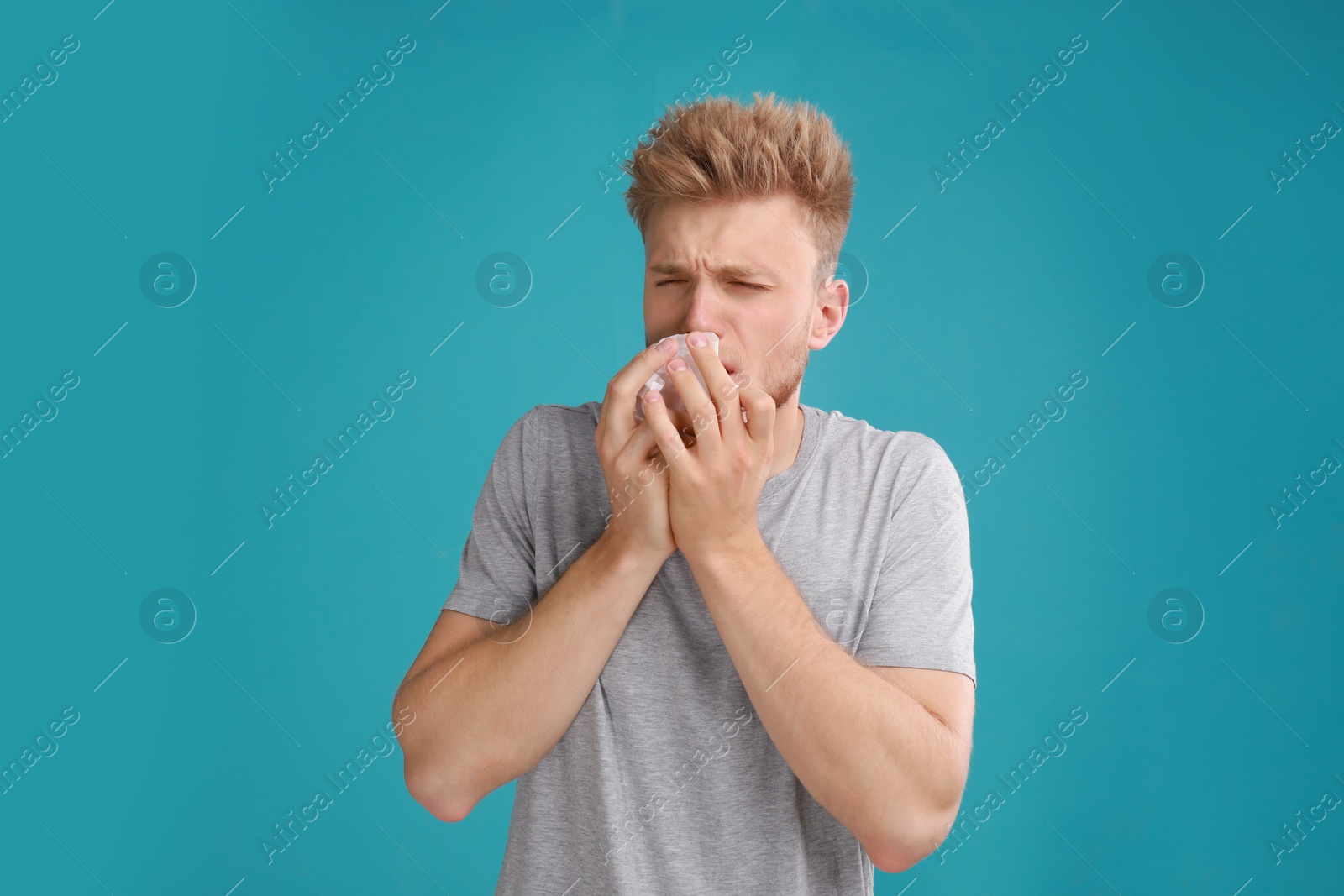 Photo of Young man suffering from allergy on blue background