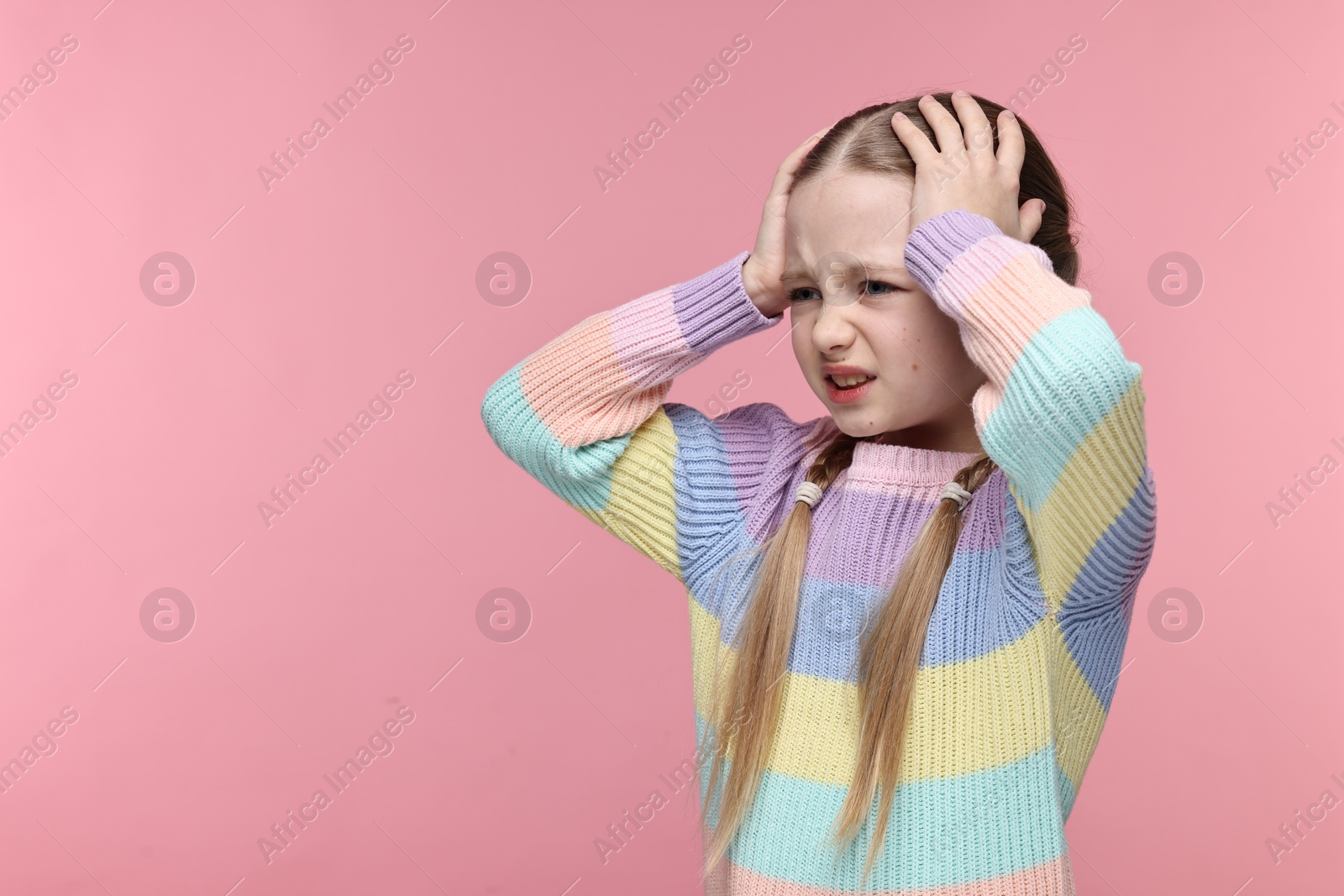 Photo of Little girl suffering from headache on pink background. Space for text