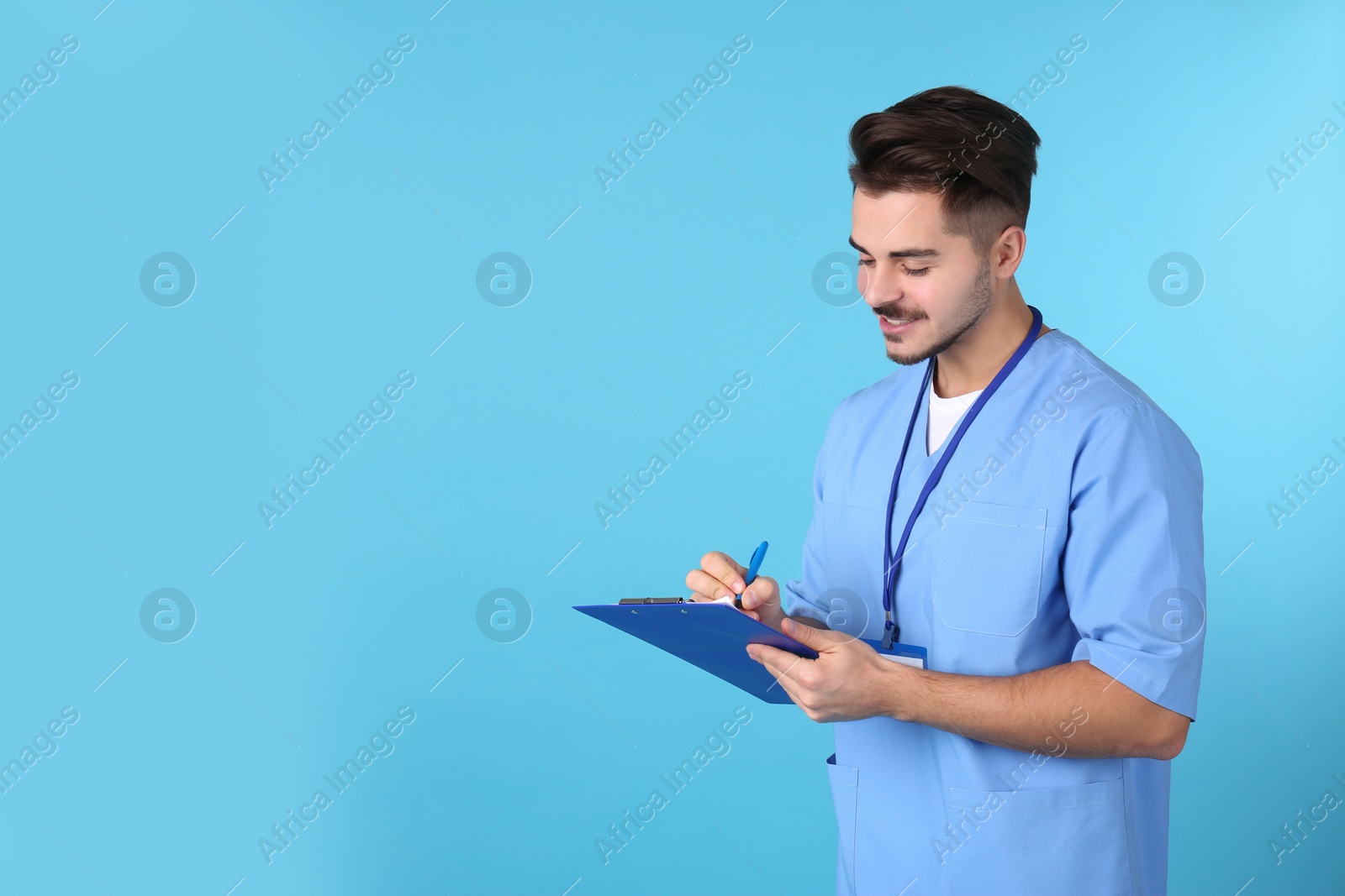 Photo of Young medical student with clipboard on color background. Space for text