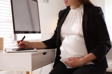 Pregnant woman working at home, closeup. Maternity leave