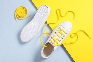 Photo of Stylish sneakers with yellow shoe laces on color background, flat lay