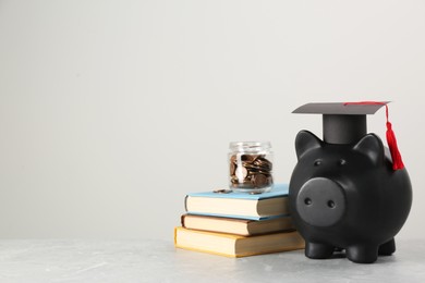 Photo of Scholarship concept. Piggy bank, graduation cap, books and coins on light grey table, space for text