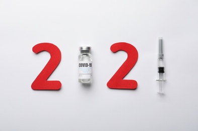 Photo of Paper numbers, syringe and vial with coronavirus vaccine forming 2021 on white background, flat lay