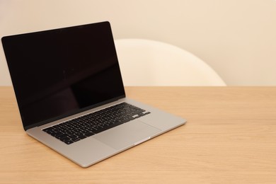 Photo of Modern laptop on wooden table. Space for text