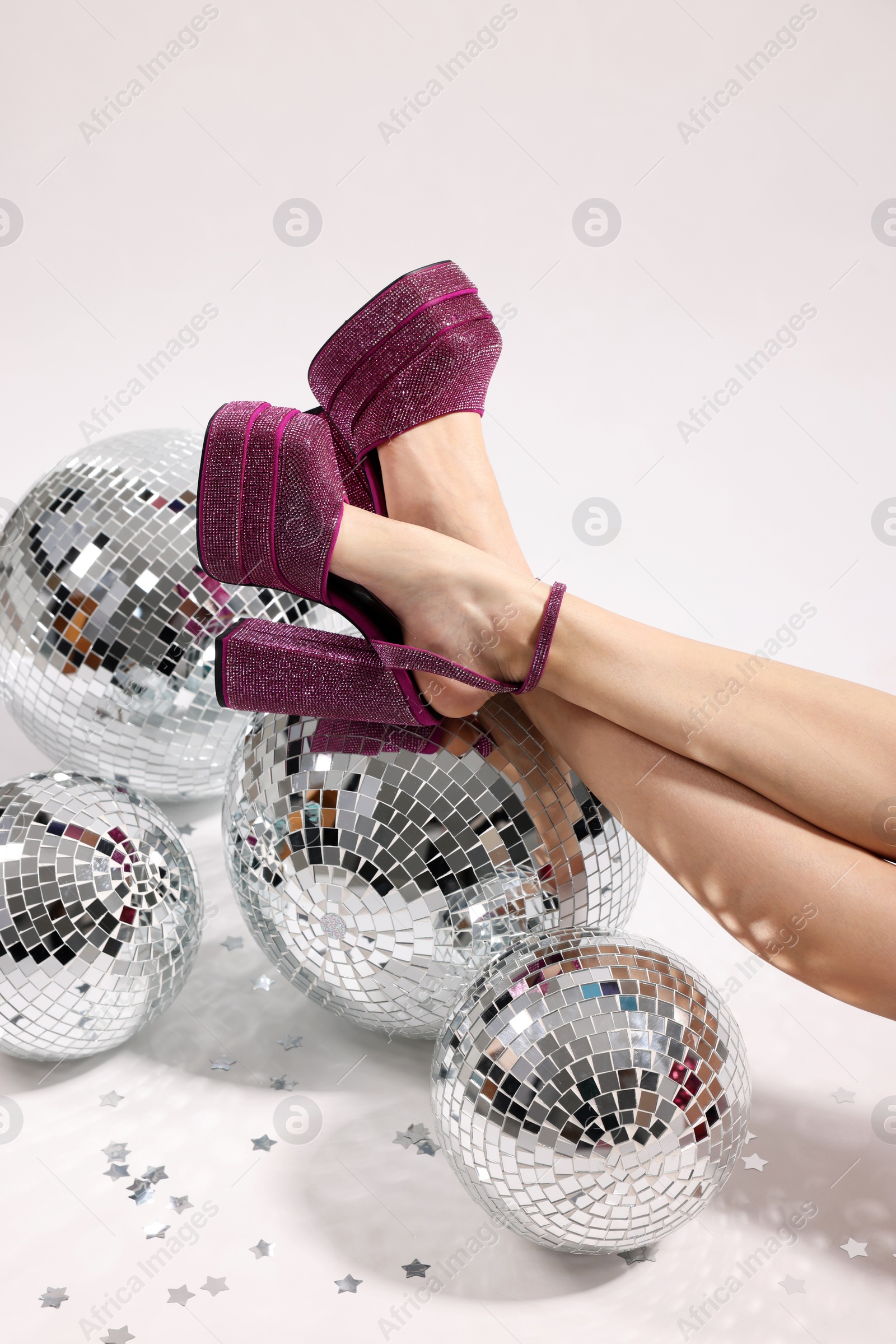 Photo of Woman in pink high heeled shoes and disco balls on white background, closeup