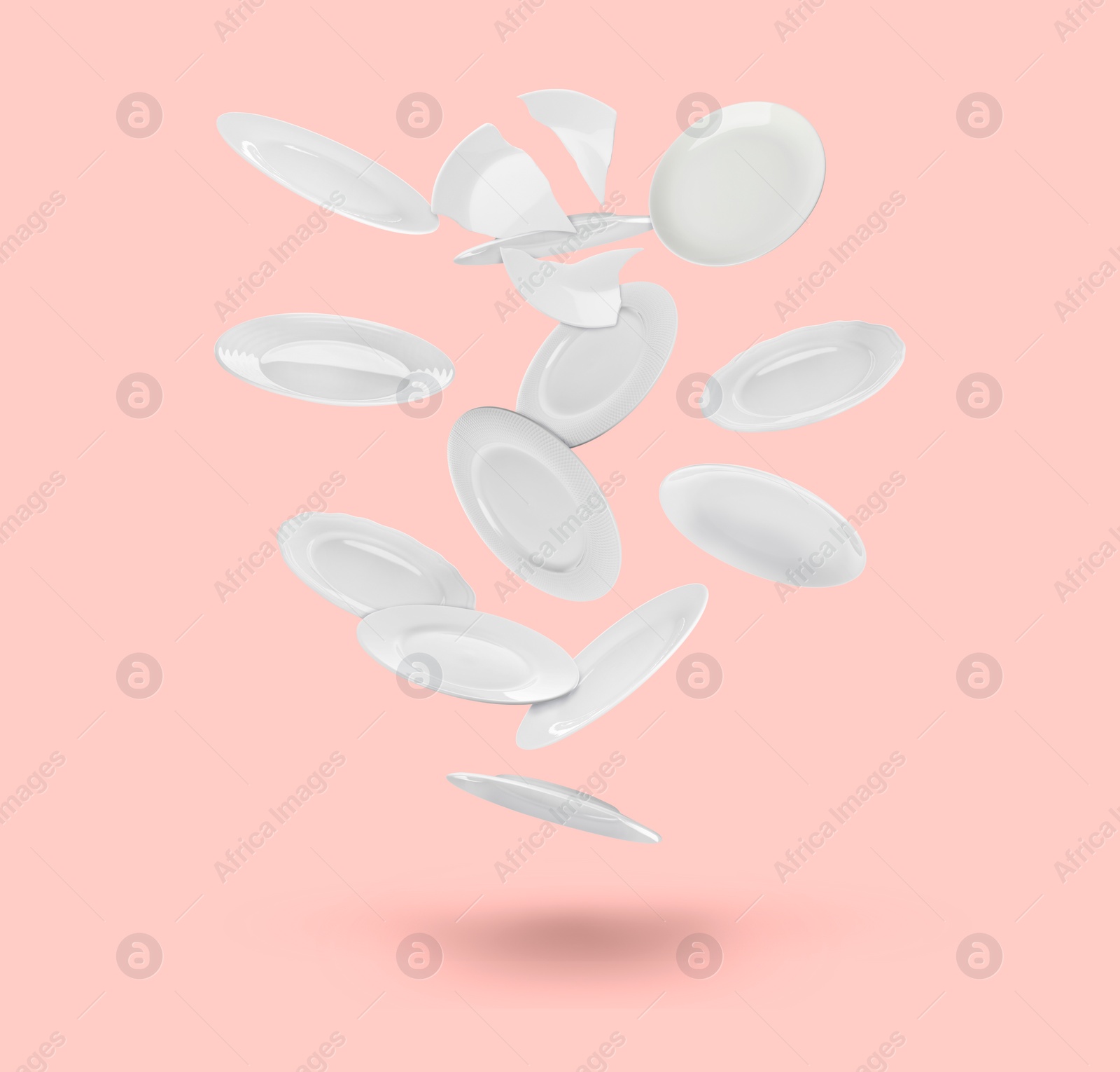 Image of Many white plates falling on pastel pink background