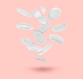 Image of Many white plates falling on pastel pink background