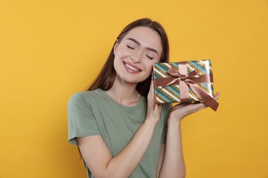 Photo of Happy young woman with gift box on yellow background