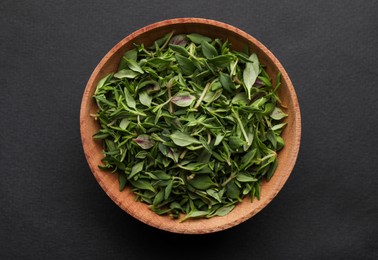 Photo of Wooden bowl of fresh green thyme leaves on dark background, top view