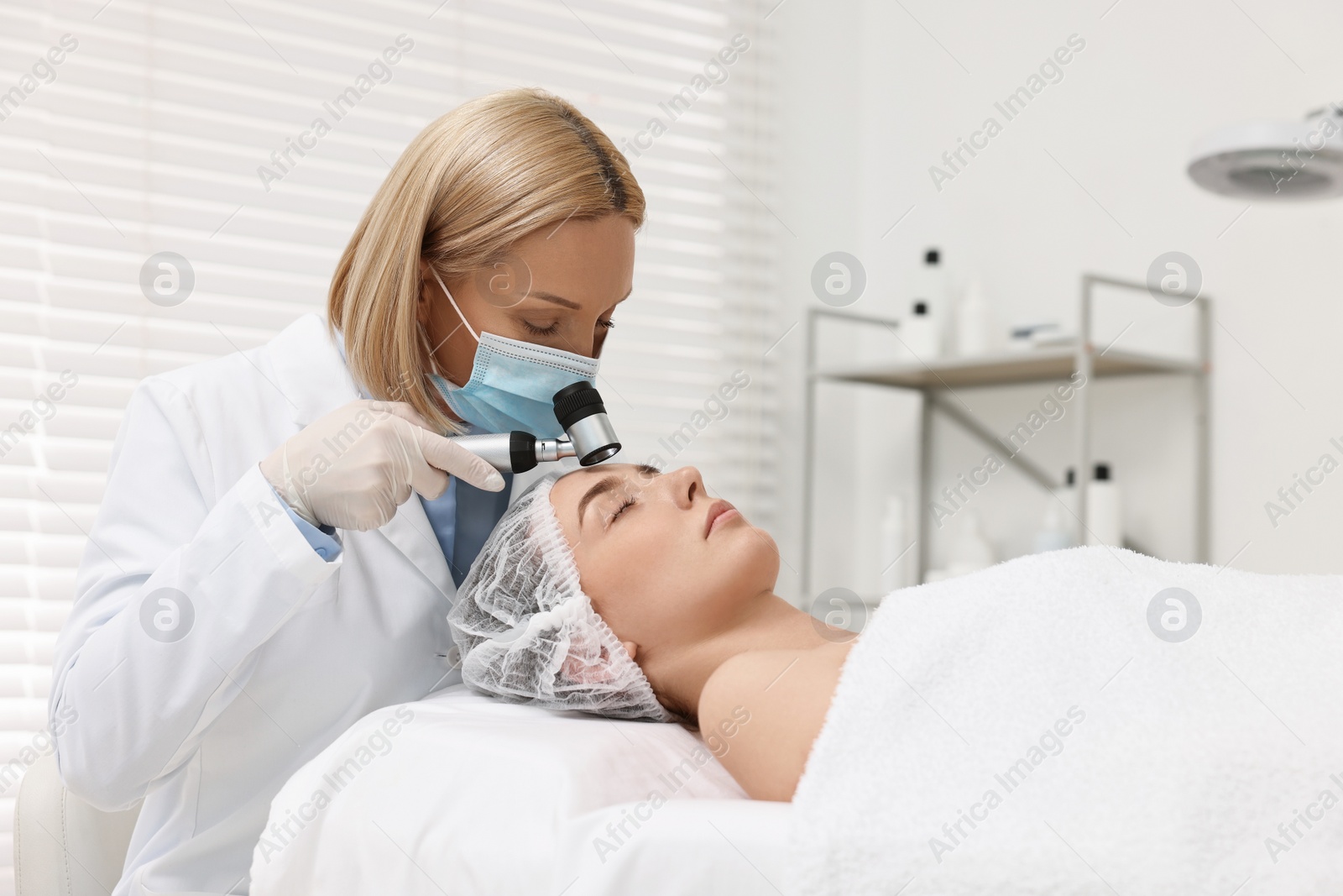 Photo of Dermatologist with dermatoscope examining patient`s face in clinic