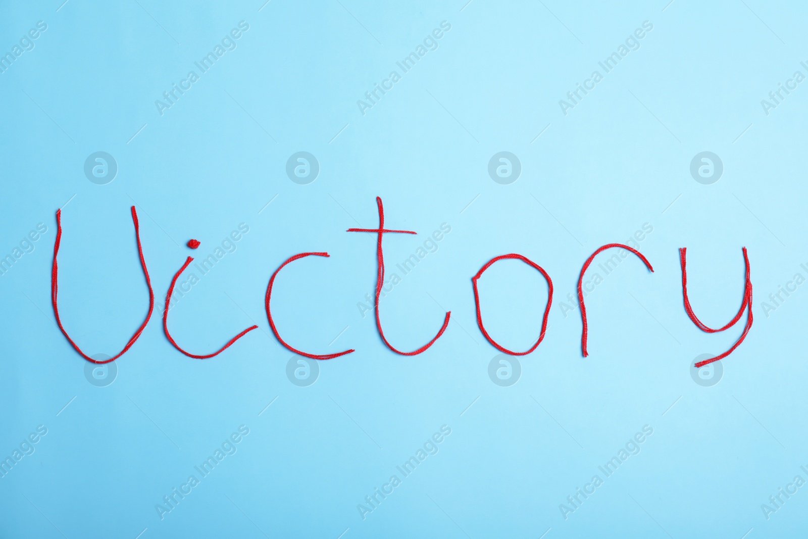 Photo of Word Victory made of threads on color background, top view