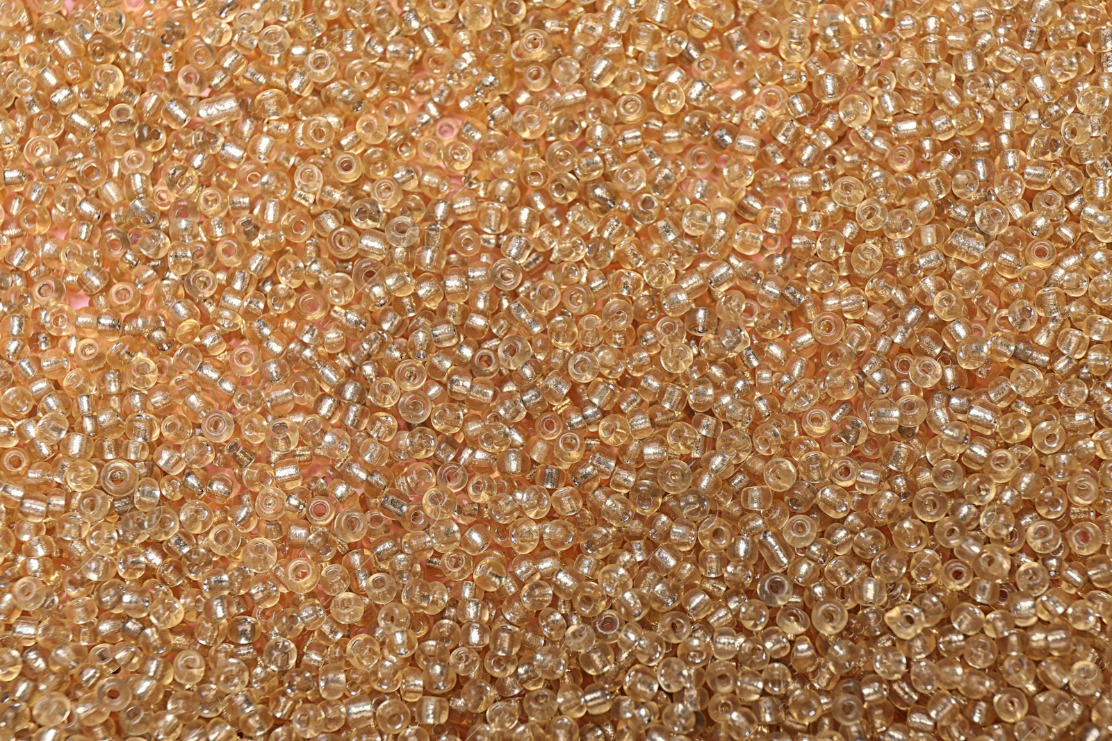 Photo of Bright golden glass beads as background, top view