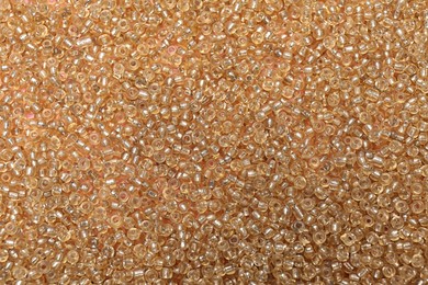 Photo of Bright golden glass beads as background, top view