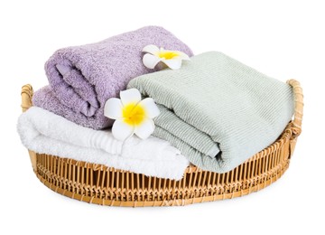 Photo of Basket with different soft towels and plumeria flowers isolated on white