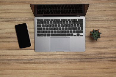 Photo of Modern laptop, houseplant and smartphone on wooden table, flat lay. Space for text