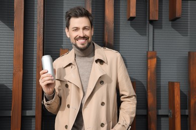 Happy man holding tin can with beverage outdoors. Space for text