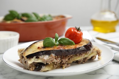 Photo of Plate of delicious eggplant lasagna served on white marble table, closeup