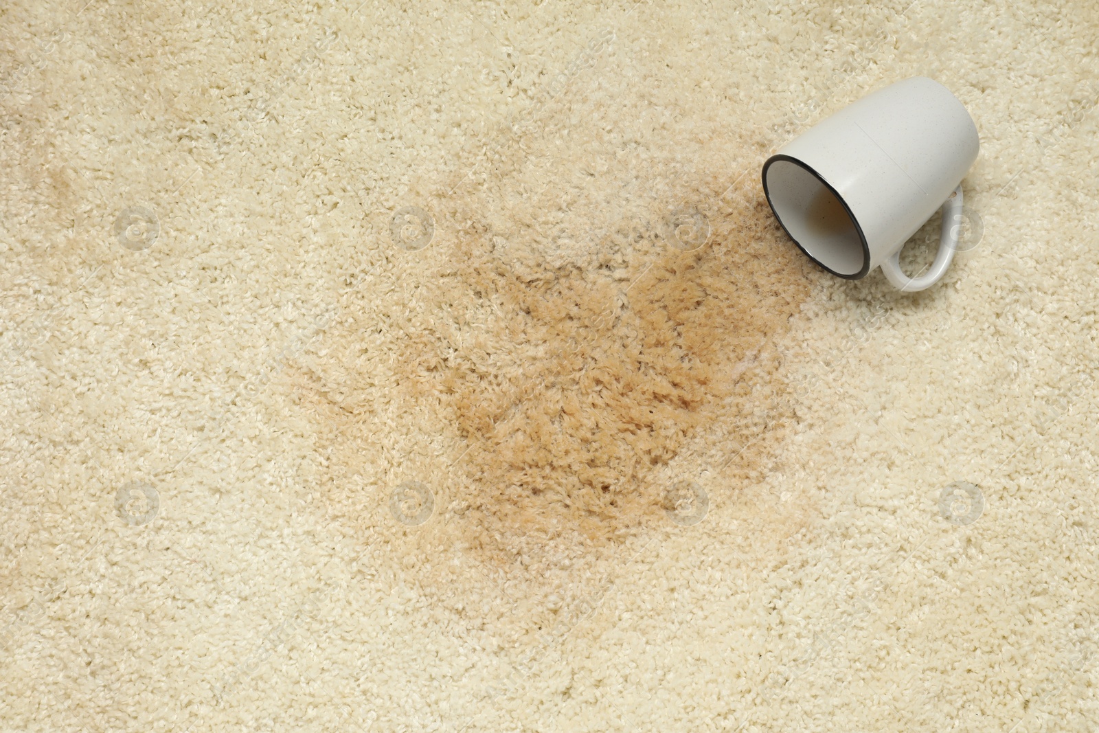 Photo of Overturned cup and spilled drink on beige carpet, top view. Space for text