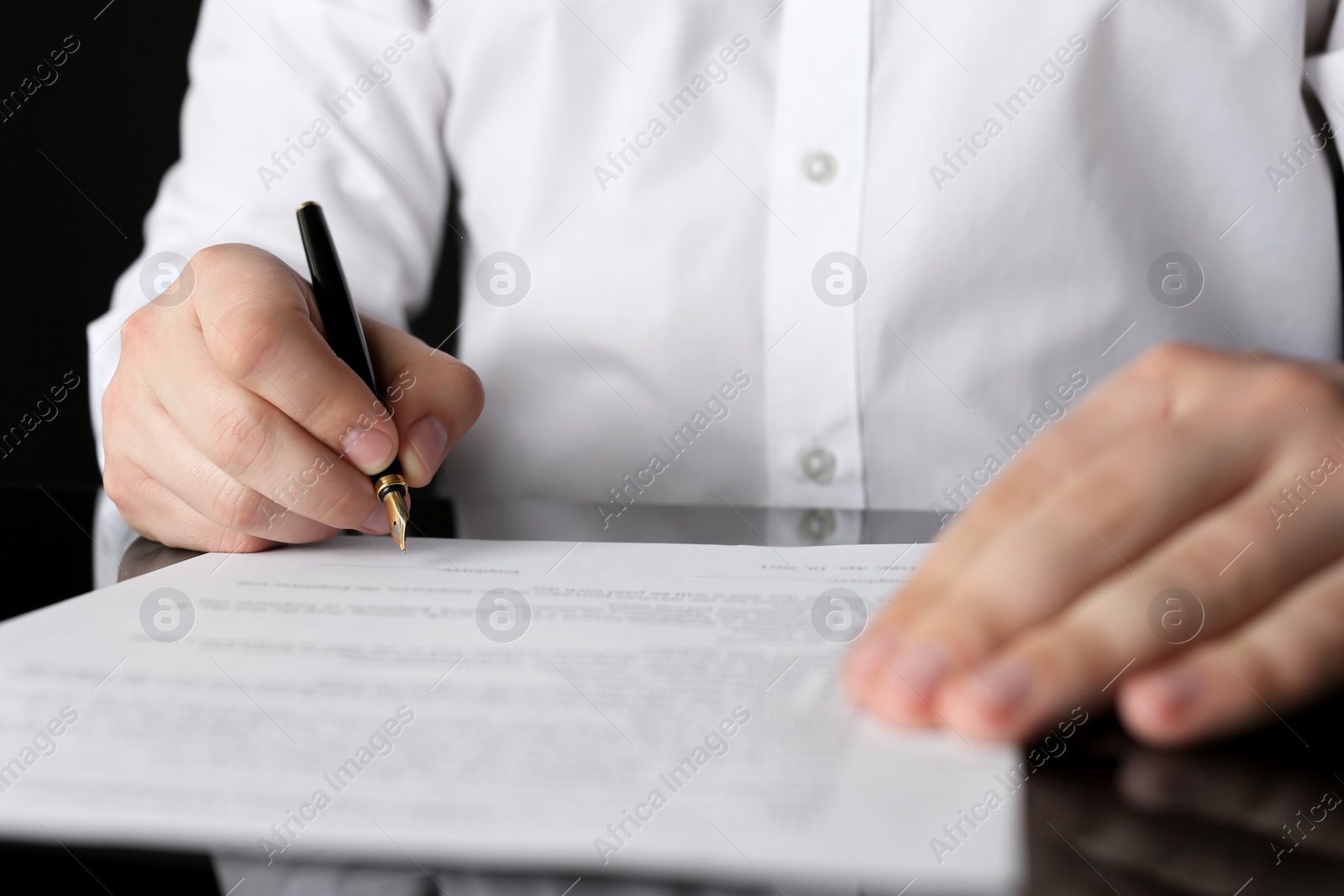 Photo of Notary signing document at black table, closeup