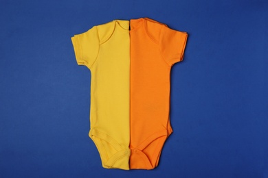 Cute baby onesies on color background, top view