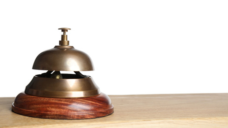 Hotel service bell on wooden table against white background, closeup