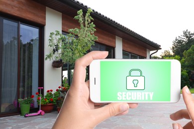 Image of Home security system. Woman with smartphone near her house outdoors, closeup