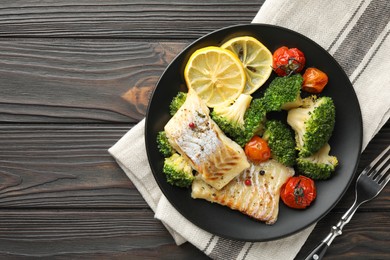Photo of Tasty cod cooked with vegetables served on wooden table, flat lay. Space for text