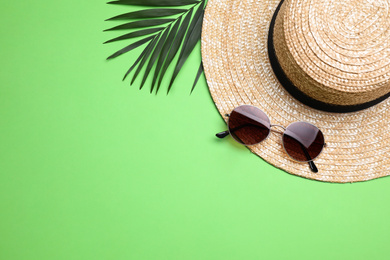 Photo of Stylish hat, sunglasses and leaf on green background, flat lay with space for text. Beach objects
