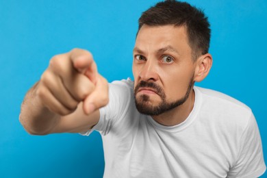 Photo of Aggressive man pointing on light blue background