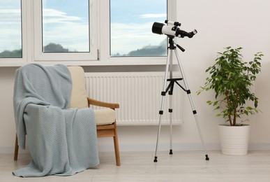 Tripod with modern telescope in stylish room